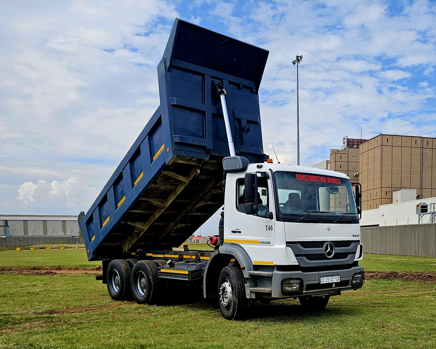 Six-wheeler tipper truck with raised bin on site